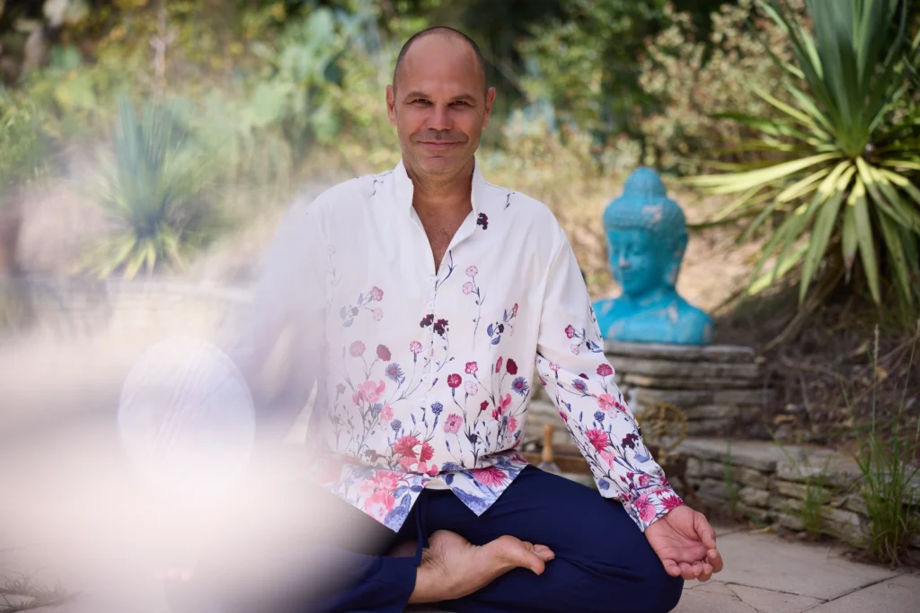 Patrick Gaveau en position du lotus, souriant et les yeux ouverts, incarnant un yoga vivant, accessible et ancré dans la joie et la présence.