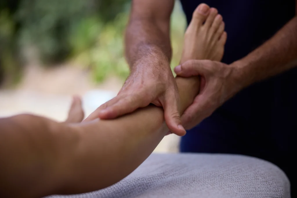 A woman lying down receives a lower leg massage, relaxed, to relieve tension and stimulate circulation.