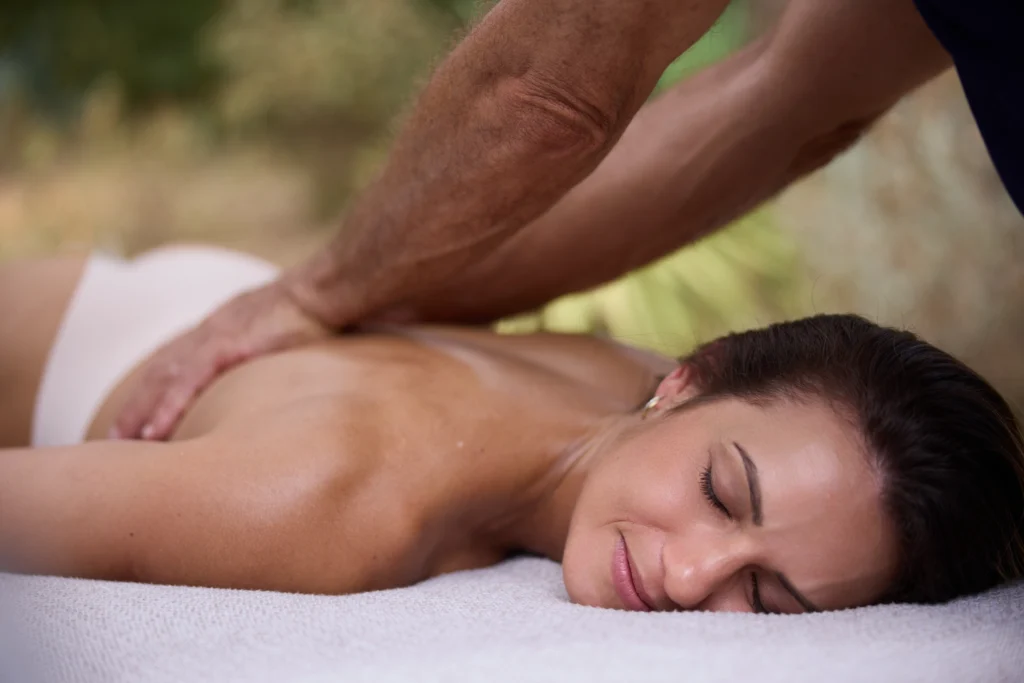 Woman lying on a massage table, back relaxed, receiving a therapeutic massage to release tension.