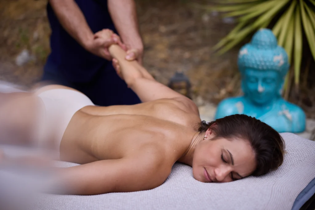 Femme allongée sur une table de massage recevant un étirement du bras pour relâcher les tensions et améliorer la mobilité.